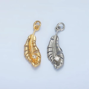 May include: Two feather charms with a clear rhinestone in the center. One charm is gold and the other is silver.