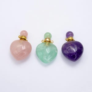 May include: Three heart-shaped crystal perfume bottles with gold stoppers. The bottles are pink, green, and purple.