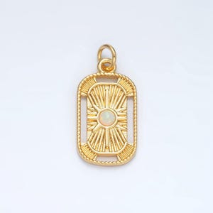 May include: Gold pendant with a white opal stone in the center of a sunburst design. The pendant is rectangular with a detailed border.