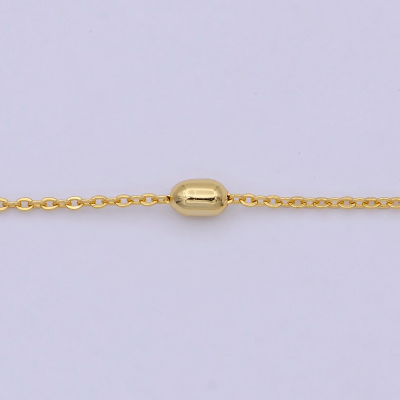 May include: A gold chain necklace with a single, round, gold bead pendant.