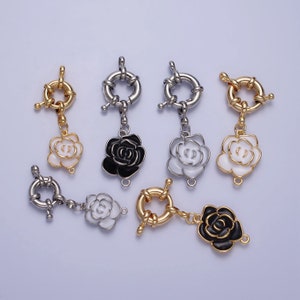 May include: Six silver and gold tone metal clasps with a rose design. The roses are either white or black enamel.