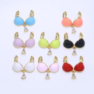 May include: Assortment of colorful enamel bra charms with a clear rhinestone dangle. The charms are gold-toned and come in a variety of colors, including pink, blue, green, red, black, and white.