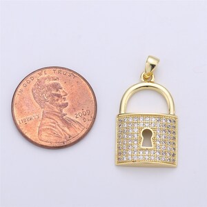 Pu&ograve; includere: Ciondolo a forma di lucchetto dorato con pietre di zircone cubico trasparenti. Il ciondolo &egrave; circa delle dimensioni di una moneta da un centesimo di euro.