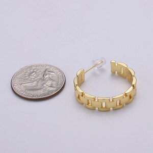 May include: Gold hoop earrings with a watch band design. The earrings are about the size of a US quarter.