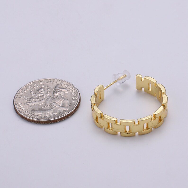 May include: Gold hoop earrings with a watch band design. The earrings are about the size of a US quarter.