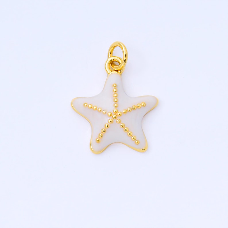 May include: A gold-colored starfish pendant with a white enamel center and gold beaded accents. The pendant has a loop at the top for attaching to a chain or bracelet. The starfish design is a popular nautical theme.