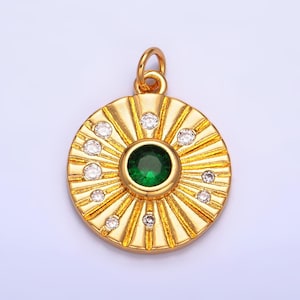 May include: Gold pendant with a green gemstone surrounded by smaller clear gemstones. The pendant has a sunburst design.