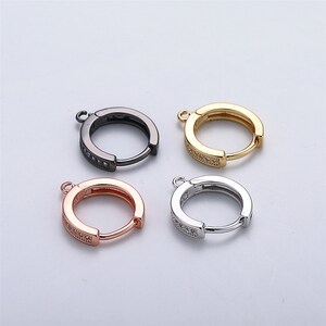 Puede incluir: Cuatro pendientes de aro con cierre de bisagra. Los aros están adornados con una fila de piedras de circonita cúbica transparentes. Los aros están disponibles en negro, oro, plata y oro rosa.