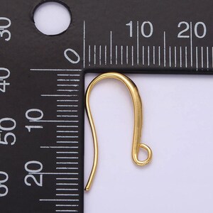 May include: Gold-toned earring hook with a loop at the end, measuring approximately 1 inch in length. The hook is shown against a black ruler.