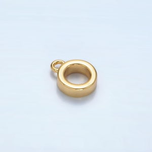 May include: A gold-colored, circular jewelry finding with a small loop at the top. The finding has a smooth, polished surface and a hollow center. The overall shape is a thick ring, suitable for jewelry making.