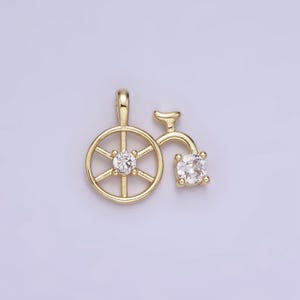 May include: Gold-toned pendant charm shaped like a bicycle with a clear crystal stone on each wheel.
