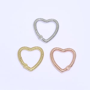 May include: Three heart-shaped metal charms in silver, gold, and rose gold. Each charm has a textured, braided design.