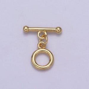 May include: Gold-toned metal toggle clasp with a round ring. The clasp is designed for attaching to necklaces, bracelets, or other jewelry.