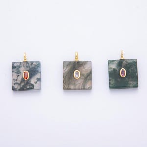 May include: Three square pendants with gold-colored bails. Each pendant features a unique pattern of green and white marbling. One pendant has an orange gemstone, another a clear gemstone, and the third a pink gemstone, all set in gold.