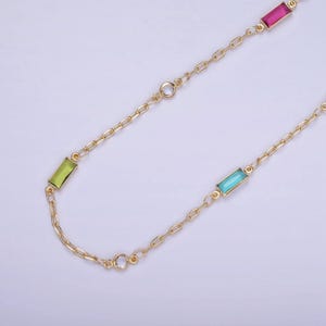 May include: A gold chain necklace with four rectangular gemstones. The gemstones are green, blue, pink, and clear.