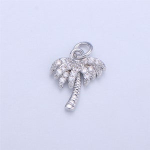 May include: A silver palm tree charm with clear cubic zirconia stones. The charm has a loop at the top for attaching to a bracelet or necklace.