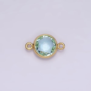 Puede incluir: Conector dorado con una piedra redonda de color azul claro. El conector tiene dos bucles a cada lado.