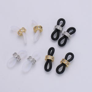Puede incluir: Seis pares de soportes para cadena de gafas con una correa de silicona transparente, negra y blanca y un anillo de metal incrustado con diamantes de imitaci&oacute;n.