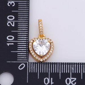 May include: A gold heart-shaped pendant featuring a large clear cubic zirconia stone surrounded by smaller cubic zirconia stones.