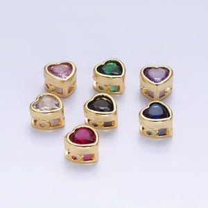May include: Seven gold heart-shaped charms with different coloured gemstones. The charms are approximately 1 cm in diameter and have a delicate, openwork design.