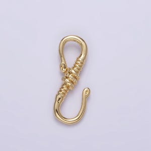 May include: A gold-toned metal clasp with a twisted design. The clasp has a hook on one end and a loop on the other.