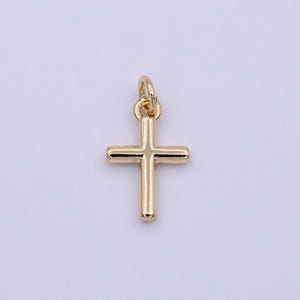 Könnte beinhalten: Ein goldfarbener Kreuz-Anhänger. Das Kreuz ist schlicht und hat eine glatte Oberfläche.