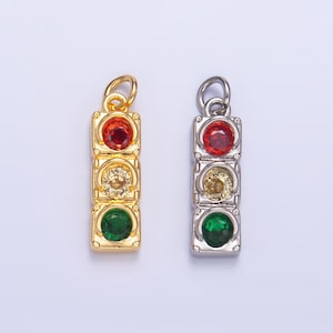 Puede incluir: Dos abalorios de semáforo de oro y plata con piedras de color rojo, amarillo y verde.