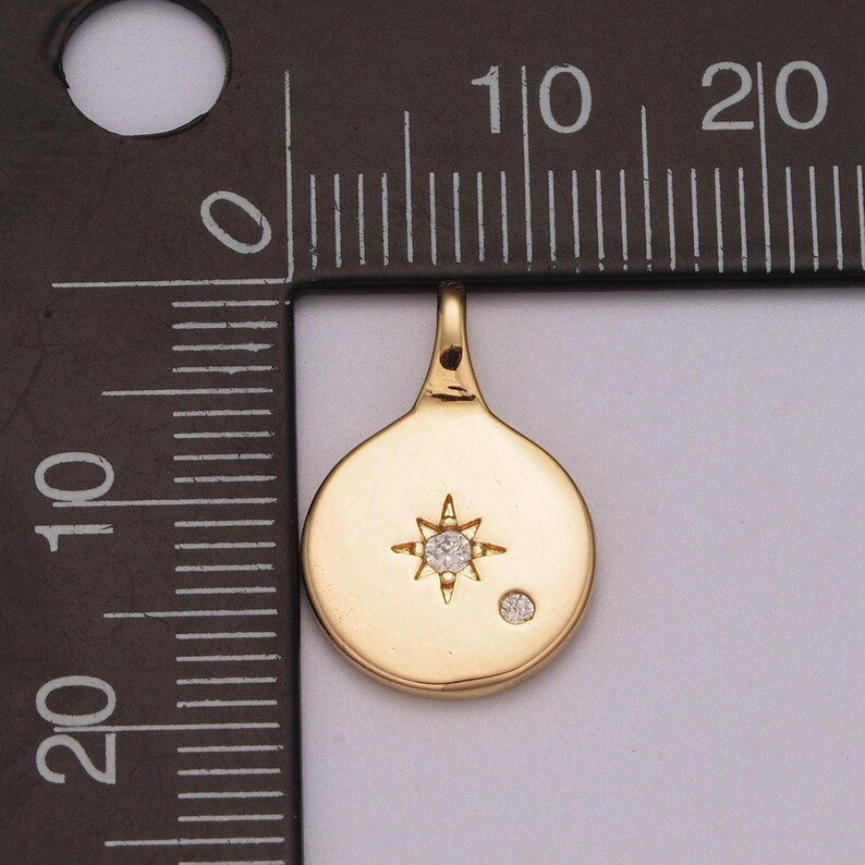 May include: Gold-toned pendant featuring a starburst design with a small diamond in the centre. A smaller diamond is also set on the pendant.