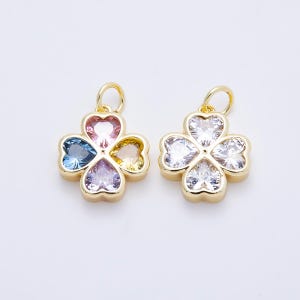 May include: Two gold-toned metal charms shaped like four-leaf clovers, each featuring four heart-shaped faceted stones. The left charm has pink, blue, yellow, and purple stones, while the right charm contains four clear, colorless stones.