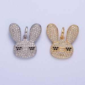 May include: Two silver and gold bunny charms with black eyes and rhinestones. The charms are in the shape of a bunny with its ears up.