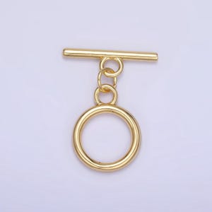 May include: Gold-toned metal toggle clasp with a round ring. The clasp is designed for attaching to a strap or chain.