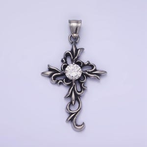 May include: A silver pendant in the shape of a cross with intricate floral details. The cross has a clear, round gemstone in the center.