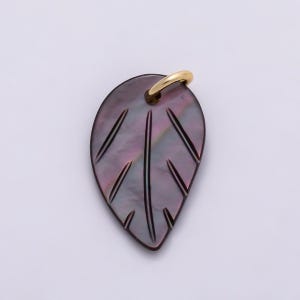 May include: A leaf-shaped pendant crafted from dark, iridescent shell material with a smooth, polished finish. The surface features carved vein details and is topped with a small, gold-toned metal jump ring for attachment to a chain or cord.