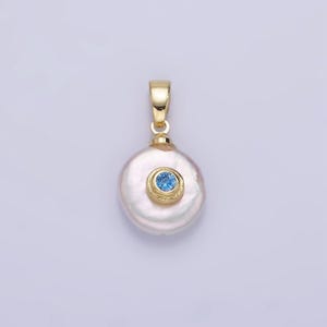 May include: A gold pendant featuring a white pearl with a blue gemstone set in a gold bezel.
