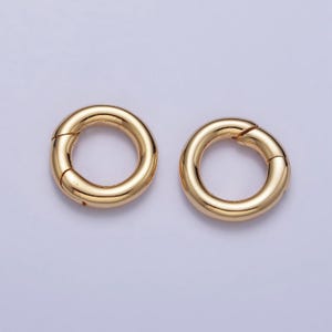 May include: Two gold-toned metal jump rings, each with a diameter of approximately 1 inch. The rings are open and have a smooth, polished finish.