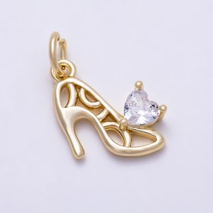 May include: A gold-toned metal charm shaped like a high-heeled shoe, featuring an openwork design and a single clear, heart-shaped cubic zirconia stone set at the toe. The charm includes a small circular jump ring at the top for attachment.