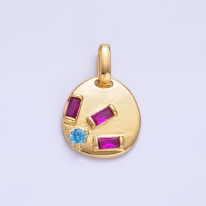 Könnte beinhalten: Ein goldener Anhänger mit einer runden, strukturierten Oberfläche und bunten Edelsteinen. Der Anhänger hat drei rechteckige rosa Steine und einen runden blauen Stein.