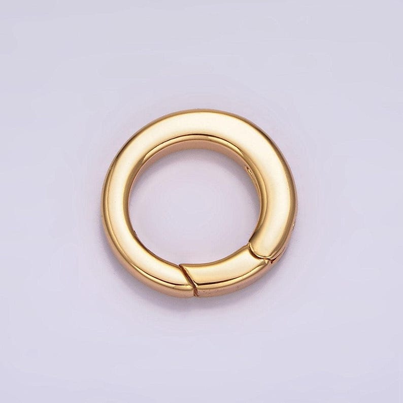 Pode incluir: Um anel de metal dourado com um fecho de mola. O anel &eacute; redondo e tem um acabamento liso e polido.