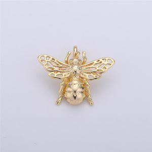 May include: A gold-toned bee charm with intricate details and a delicate, openwork design. The charm is perfect for adding a touch of nature to jewelry projects.