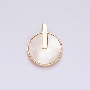 May include: A gold pendant with a white mother-of-pearl circle and a gold bar in the center.