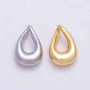 May include: Two teardrop-shaped pendants, one in a polished silver-tone finish and the other in a smooth gold-tone finish. Each pendant features a hollow center and a rounded, organic form, presented side-by-side against a plain background.