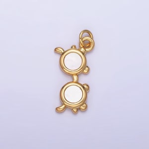 May include: Gold-tone charm in the shape of a pair of glasses with white pearl-like lenses.