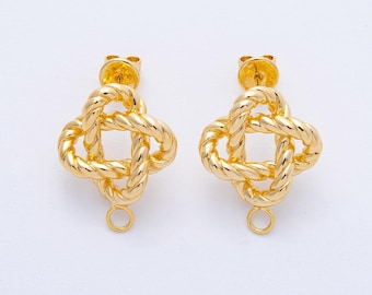 May include: A pair of gold-coloured stud earrings. Each earring has a woven, four-leaf clover design with a post and a small loop at the bottom. The earrings are set against a white background.