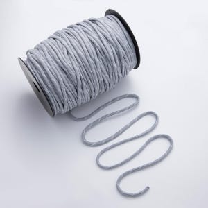 May include: A spool of gray and white cord. The cord is tightly wound around a black plastic spool. A length of the cord is unwound and lies in a wavy pattern on a white surface. The cord has a subtle pattern.