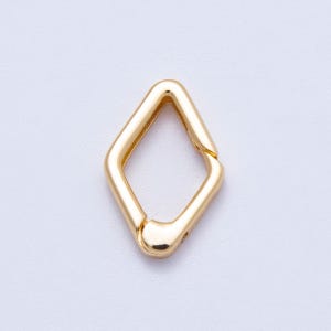 May include: A gold-colored, diamond-shaped clasp. The clasp is a single piece of metal with a hinged opening on one side. The metal has a smooth, polished finish. The clasp is set against a white background.