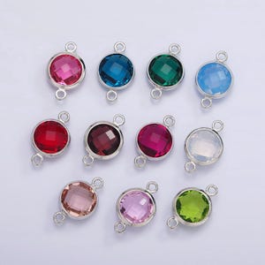 May include: Assortment of 10 round, faceted glass charms with silver-toned jump rings. The charms are in various colors, including red, pink, green, blue, and clear.