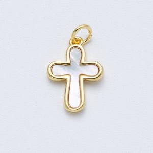 May include: Gold-colored cross pendant with a white, pearlescent center. The cross has rounded edges and a small loop at the top for a chain. The pendant is likely made of gold-plated metal.