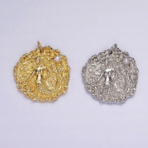 May include: Two mermaid pendant charms, one gold and one silver, with a pearl accent. Both charms feature a detailed mermaid design with flowing hair and a tail.