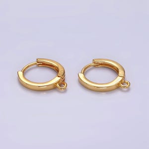 May include: A pair of gold-toned hoop earrings with a hinged closure and a small jump ring on each earring.