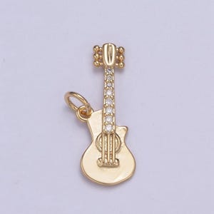 May include: Gold-tone guitar charm with clear crystal accents. The charm has a loop for attaching to a necklace or bracelet.